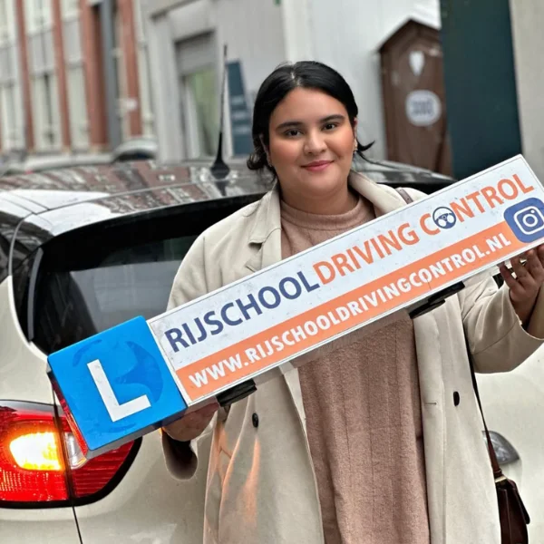 Geslaagde autoleerling met Rijschool Driving Control reclamebord voor lesauto in Rotterdam — autorijbewijs B automaat gehaald