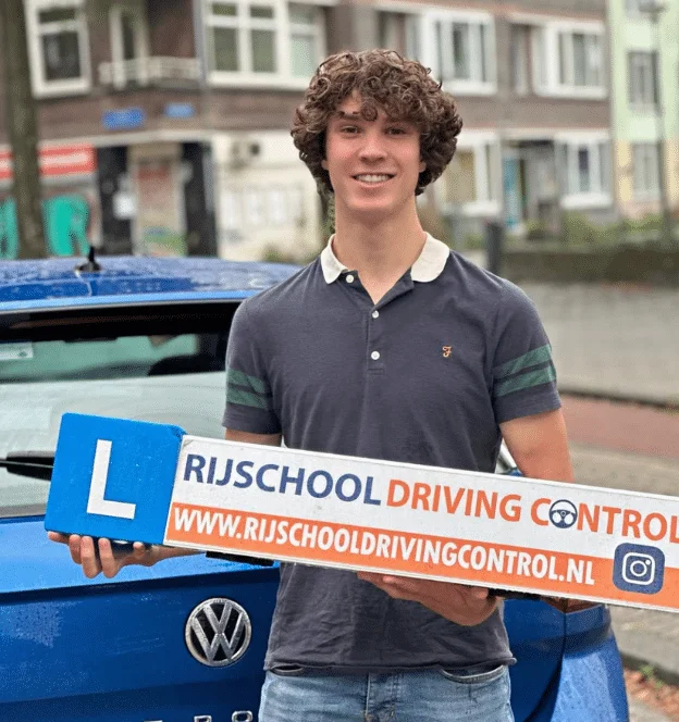Jonge geslaagde leerling met Rijschool Driving Control bord bij lesauto in Rotterdam — autorijbewijs B schakel gehaald